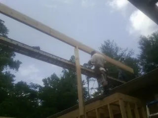 Carpenter setting a ridge beam over a new addition frame — Ice Dam Removal by Roofing Brothers in Whitten