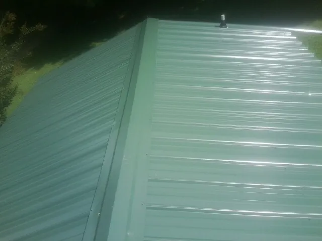 New green metal panels meeting at the ridge of a roof — Flat Roof Repair work by our crew in Whitten
