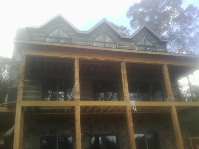 Dormers and porch framing on a large log home under construction — Roof Coating work by our crew in Whitten