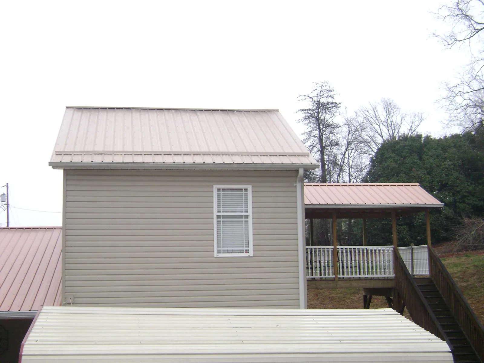Tan metal roofs on a two story addition and attached porch, from a Roof Replacement job in Whitten